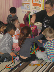 Pre-school children with their keyworker, playing with ribbon